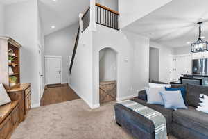Living room with high vaulted ceiling, carpet flooring, baseboards, recessed lighting, and an inviting chandelier