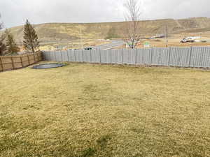View of back yard with fence, ground-level trampoline, and a mountain view