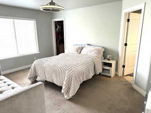 Main bedroom with baseboards, carpet, a spacious closet, and en-suite bath