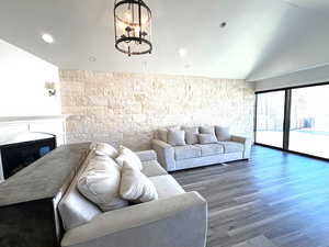 Living room with recessed lighting, a glass covered fireplace, vaulted ceiling, and wood finished floors