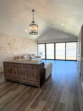 Unfurnished living room with lofted ceiling, dark wood-style floors, and a chandelier