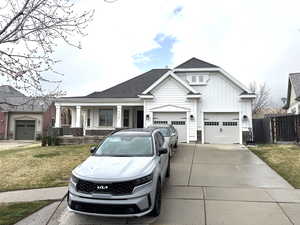 Modern farmhouse style home featuring roof with shingles, concrete driveway, fence, an attached garage, and a front lawn