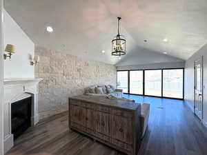 Bedroom with access to outside, lofted ceiling, dark wood-style flooring, and a chandelier