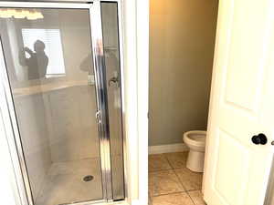 Main bathroom with baseboards, toilet, tile patterned flooring, and a shower stall