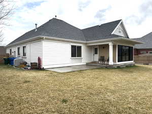 Back of property featuring a patio, a shingled roof, fence, and a large yard