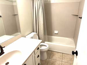 Bathroom featuring vanity, toilet, tile patterned flooring, and shower/tub combo with curtain