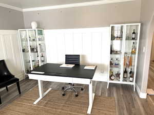 Office area featuring a decorative wall, ornamental molding, and wood finished floors