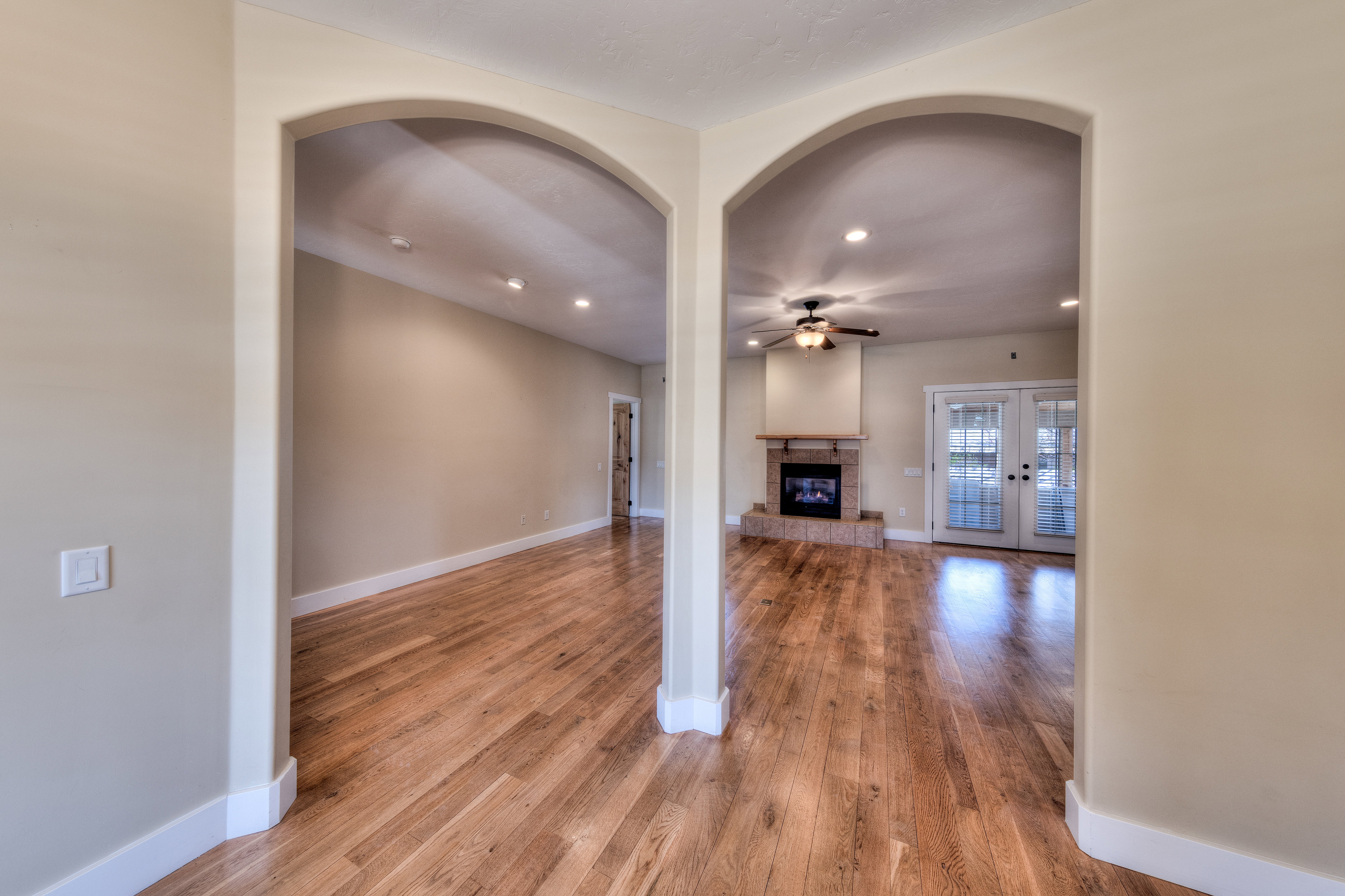 Unfurnished living room featuring baseboards, wood finished floors, a glass covered fireplace, and a ceiling fan