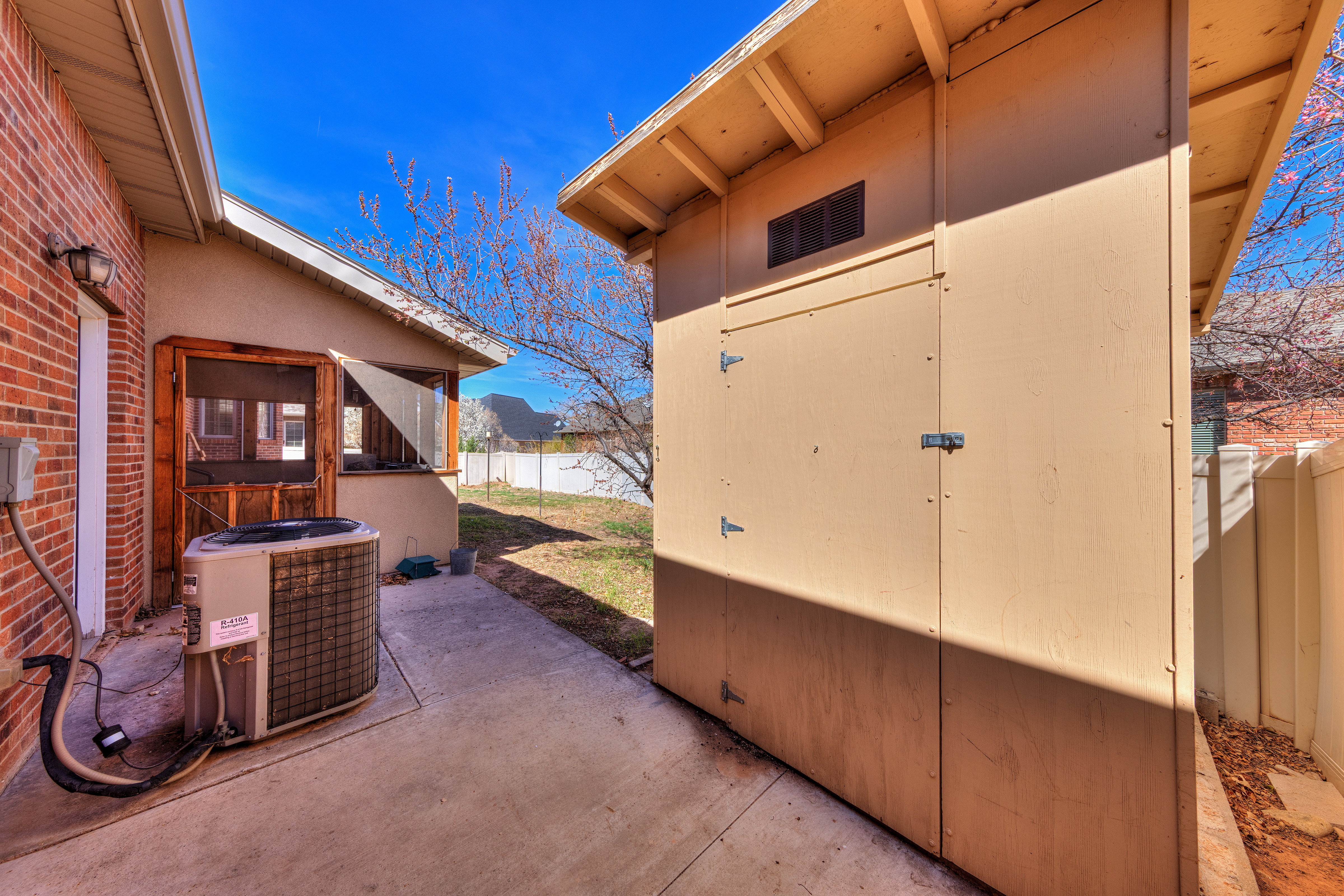 View of patio featuring an outbuilding, cooling unit, a shed, and a fenced backyard