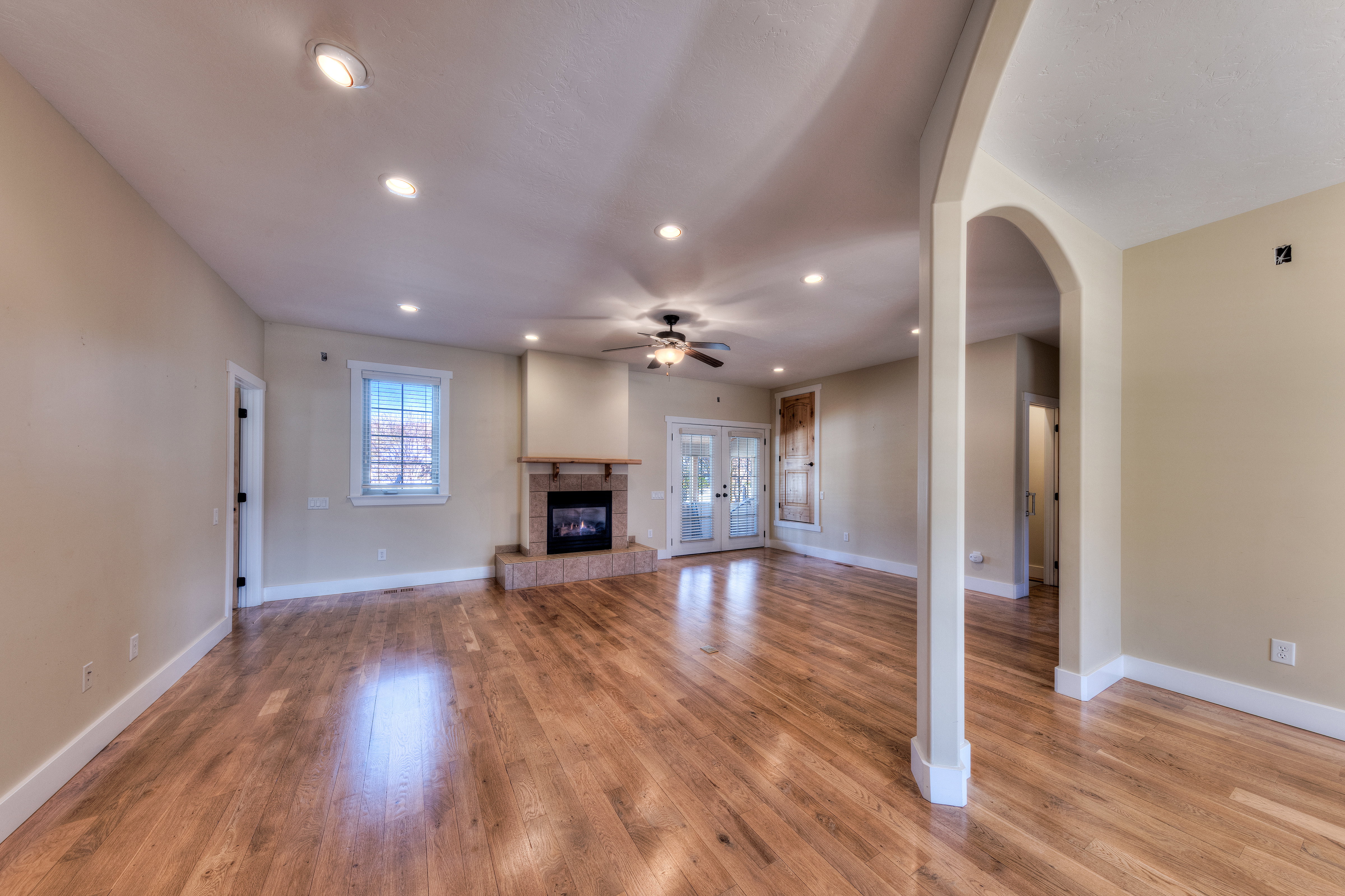 Unfurnished living room with baseboards, a tiled fireplace, light wood-style flooring, and a ceiling fan