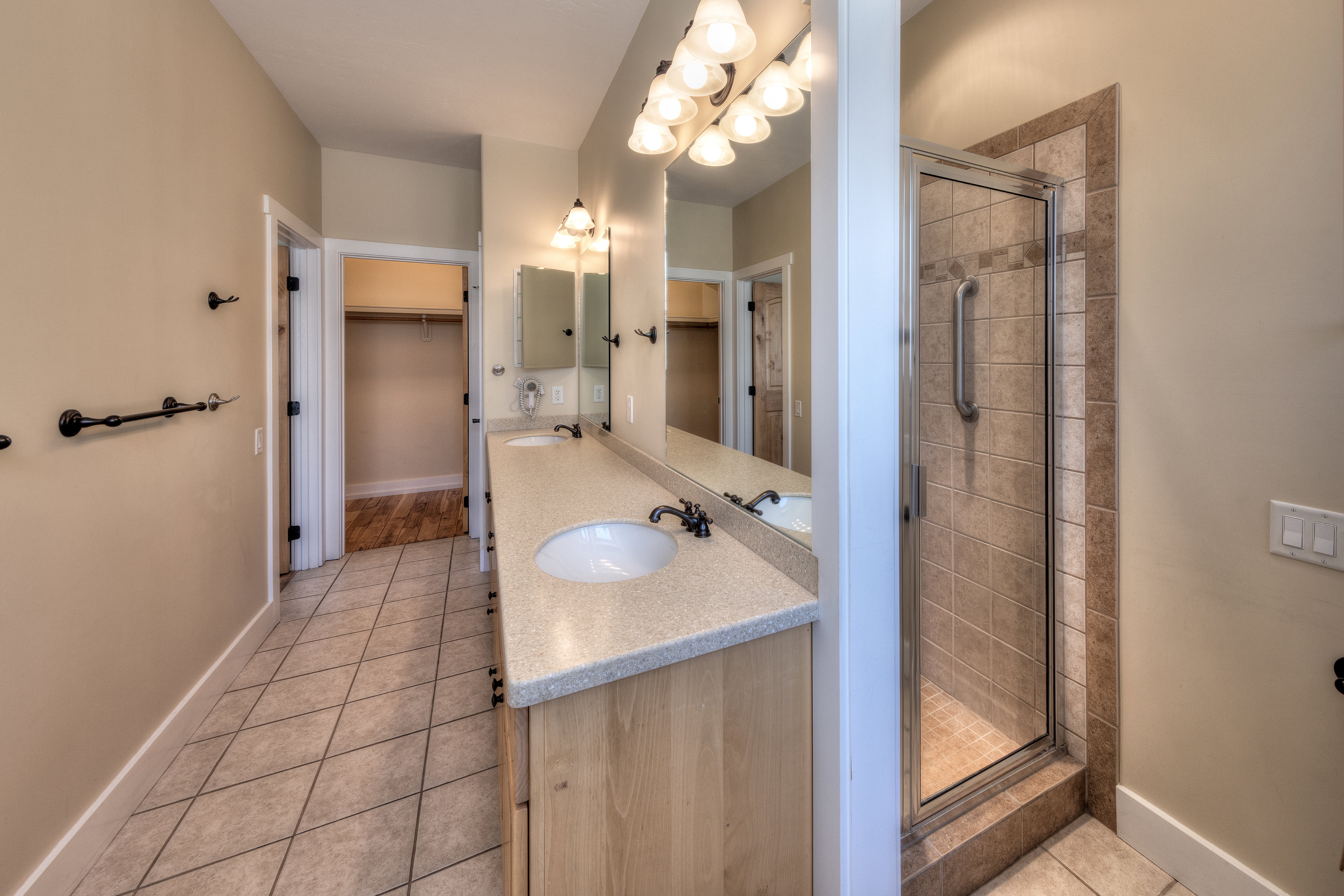 Bathroom featuring a walk in closet, a sink, tile patterned flooring, and a shower stall