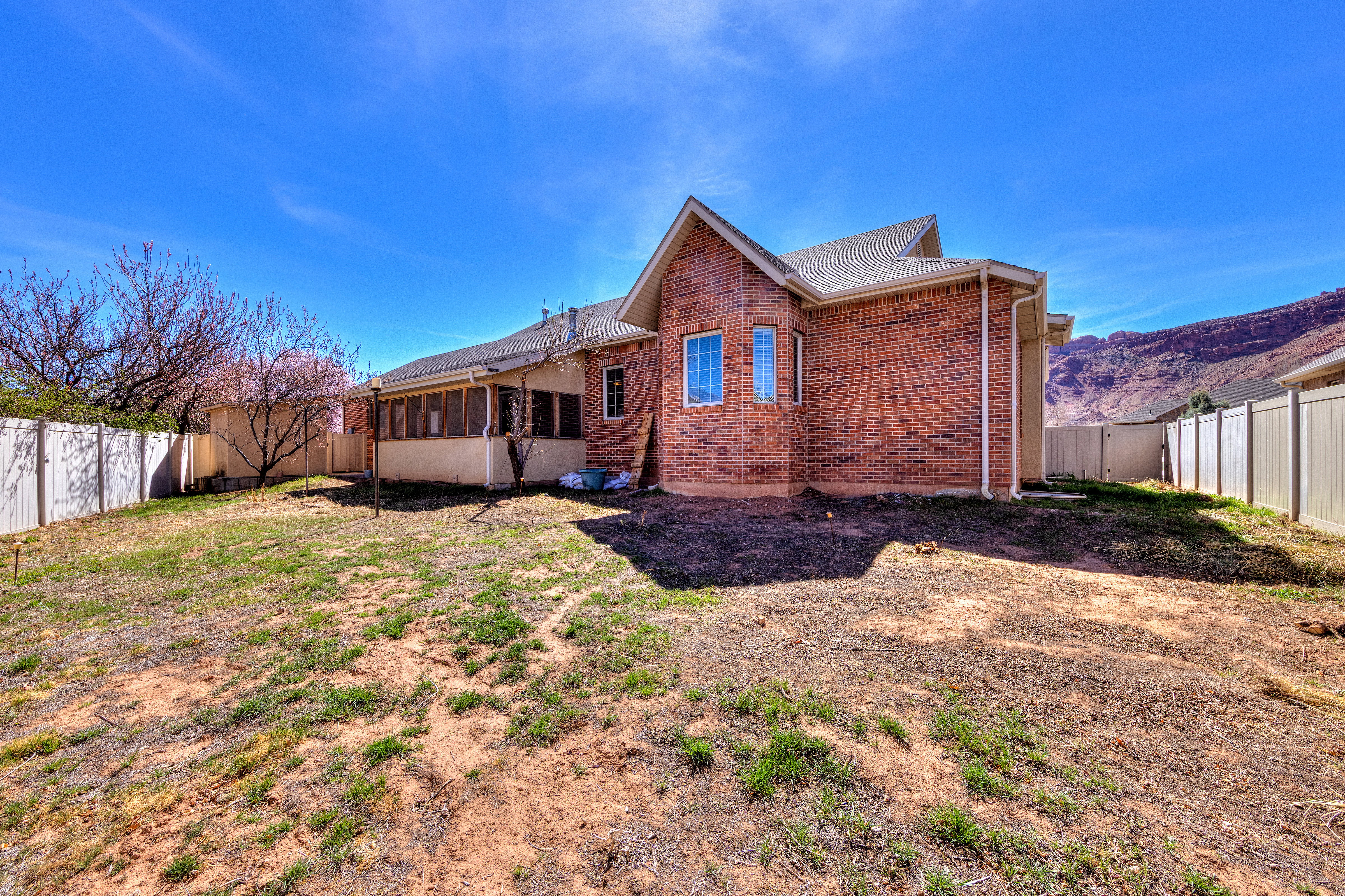 Rear view of property with a fenced backyard, brick siding, and roof with shingles