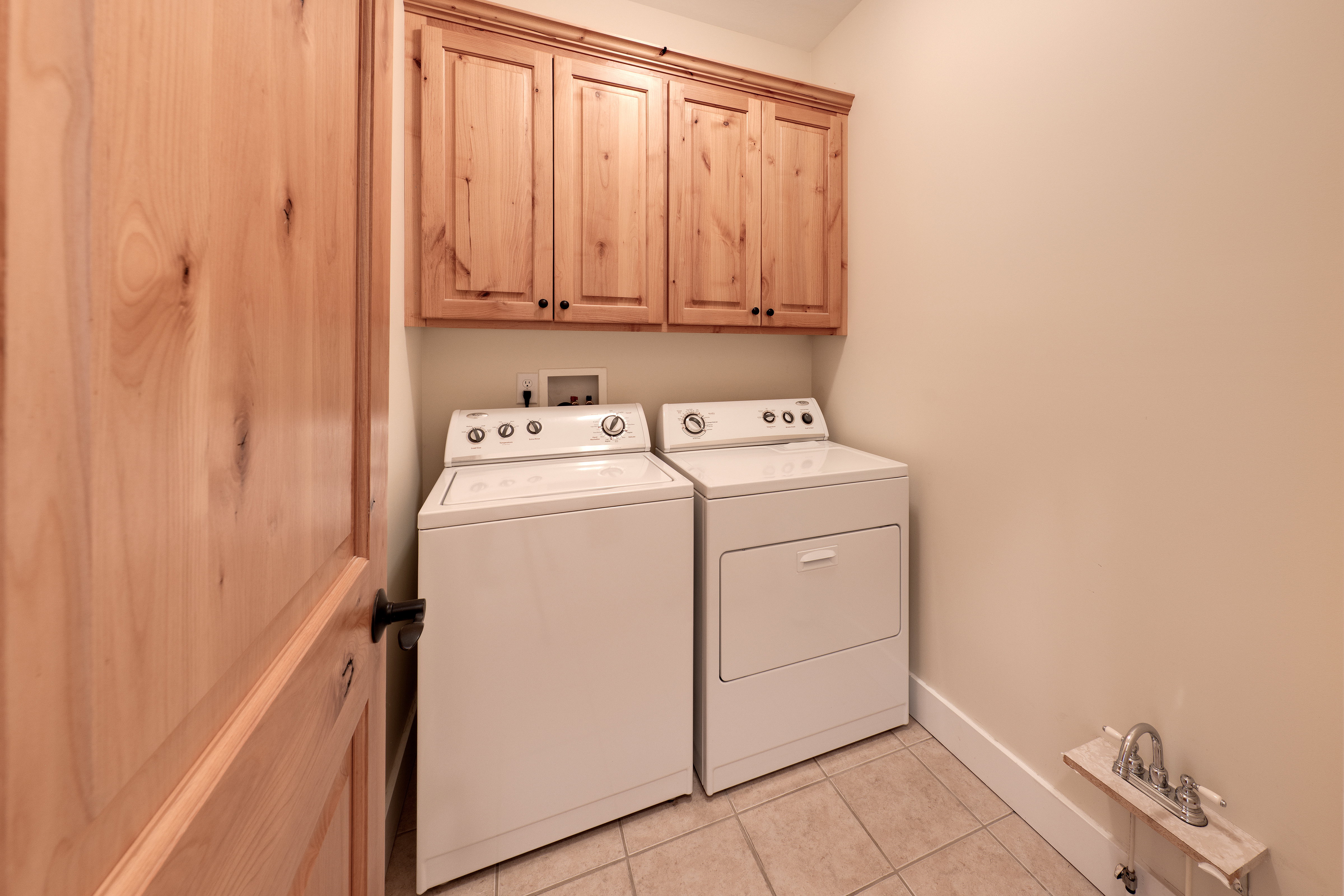 Laundry room with light tile patterned floors, cabinet space, baseboards, and washer and dryer