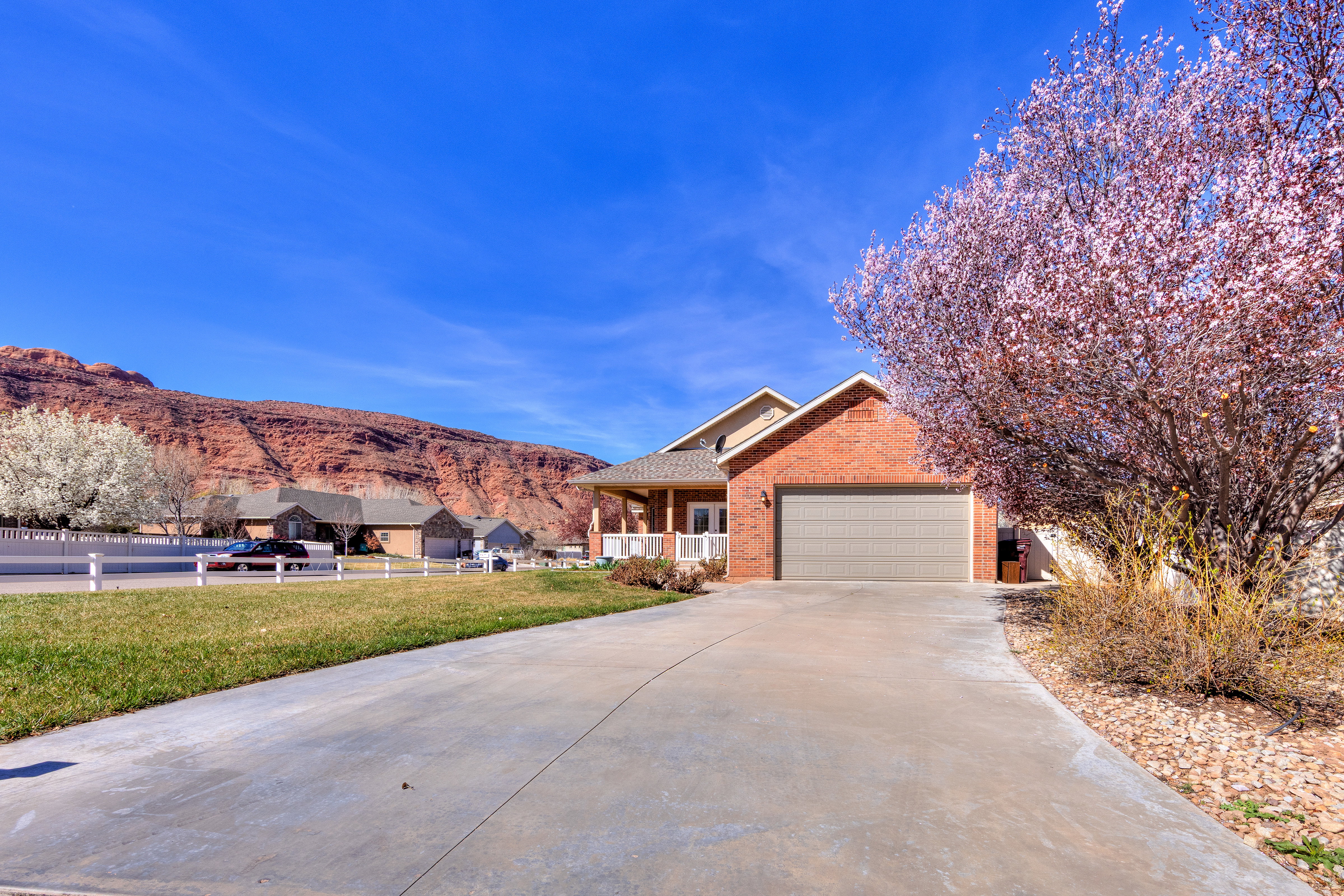 View of front of house featuring an attached garage, a front yard, brick siding, driveway, and a mountain view