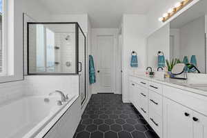 Full bath with a bath, a shower stall, double vanity, a sink, and tile patterned flooring