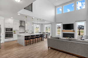 Living area featuring recessed lighting, light wood-style flooring, a glass covered fireplace, and a healthy amount of sunlight