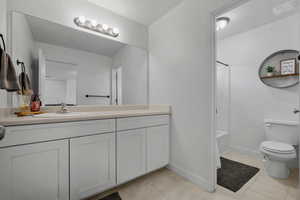 Bathroom with vanity, toilet, baseboards, bathing tub / shower combination, and tile patterned floors