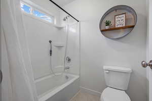 Bathroom featuring baseboards, toilet, and shower / bath combo with shower curtain