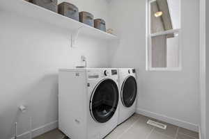 Laundry area featuring light tile patterned flooring, visible vents, baseboards, laundry area, and washing machine and dryer