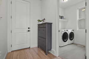 Laundry area with visible vents, baseboards, laundry area, light wood-style floors, and washer and dryer