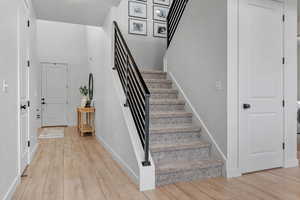 Foyer with baseboards, light wood-style floors, and stairway