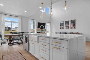 Kitchen featuring light countertops, light wood-type flooring, a sink, dishwasher, and white cabinets