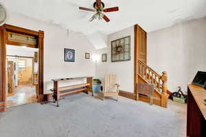 Living area with stairs, ceiling fan, and carpet flooring