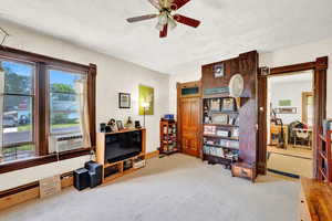 Interior space with carpet flooring, a ceiling fan, and a textured ceiling