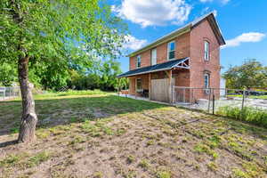 Rear view of house featuring a lawn, brick siding, fence, and a patio area