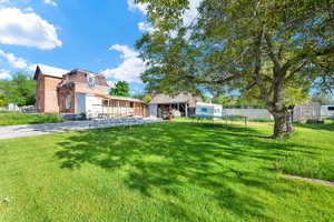 View of yard featuring fence, a storage shed, a garage, concrete driveway, and an outbuilding