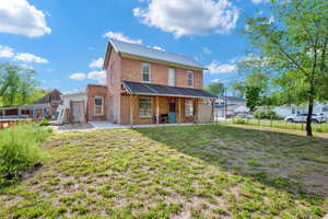 Back of property with a patio area, brick siding, a fenced backyard, metal roof, and a yard