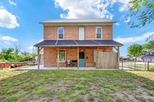 Back of property featuring a lawn, brick siding, fence, and metal roof