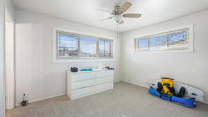 Interior space with carpet flooring, a ceiling fan, and baseboards