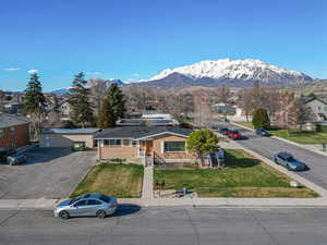 View of front facade featuring uncovered parking, a front yard, brick siding, a residential view, and a mountain view