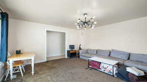 Carpeted living area with baseboards and a chandelier