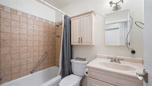 Full bath featuring shower / tub combo with curtain, toilet, and vanity
