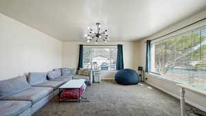 Carpeted living room with a notable chandelier and baseboards