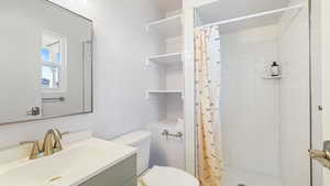 Full bath with toilet, vanity, and a stall shower