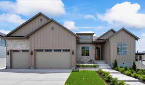 View of front of property featuring board and batten siding, driveway, a garage, and stone siding