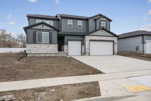 View of front facade with stone siding, concrete driveway, and a garage