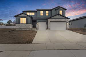 View of front of property with stone siding, driveway, and an attached garage