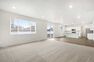 Unfurnished living room featuring light carpet, baseboards, and recessed lighting