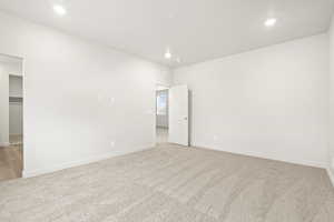 Unfurnished bedroom with recessed lighting, light carpet, baseboards, and a spacious closet