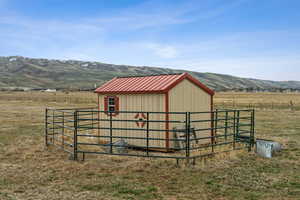 View of outbuilding with a rural view, an outbuilding, fence, and a mountain view