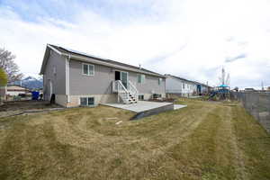 Rear view of property featuring a patio area, a playground, a fenced backyard, solar panels, and a yard