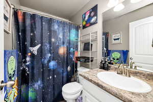 Bathroom featuring a shower with shower curtain, toilet, and vanity