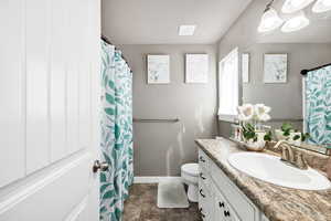 Bathroom with toilet, vanity, baseboards, and visible vents