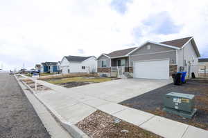 Ranch-style house with stone siding, an attached garage, and concrete driveway