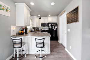 Kitchen featuring a peninsula, baseboards, appliances with stainless steel finishes, a sink, and light wood-style floors