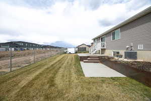 View of yard featuring cooling unit, fence, and a patio area